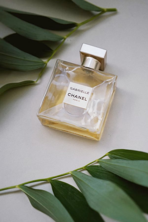 It's a yellow perfume from CHANEL, which lies on the table with green liefs